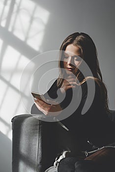 Portrait of a young sad crying girl with a smartphone in her hand.