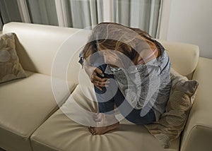 Portrait of young sad and depressed girl crying desperate at home couch feeling broken heart suffering depression crisis and