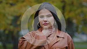 Portrait young sad hispanic woman standing outdoors feeling sore throat suffering from painful symptoms flu infection