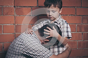 Portrait of young sad little boy and father sitting outdoors at the day time