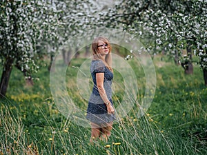 Portrait of a young school teacher with glasses in a spring green apple garden