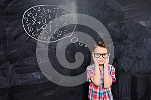 Portrait of young schoolboy in glasses trying to solve difficult task