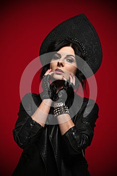 Portrait of sensual sexy woman in stylish neofolk clothes black leather jacket and kokoshnik on dark red
