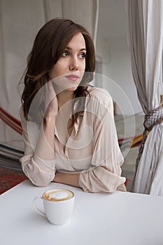 Portrait of young sensual woman drinking coffee on a cafe veranda. Concept of relaxation and city leisure