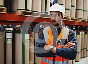 Portrait of a young serious african american man with folded hands and white hard hat standing in manufacturing