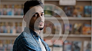 Portrait of young serious arabic model man with beard in plaid shirt standing indoors posing looking at camera close-up