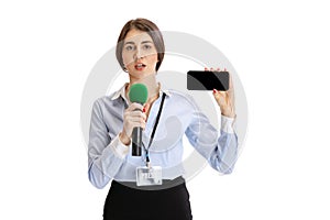 Portrait of young serious girl, correspondent showing phone screen isolated on white studio background. Concept of