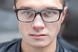 Portrait of a young serious guy nerd in eyeglasses