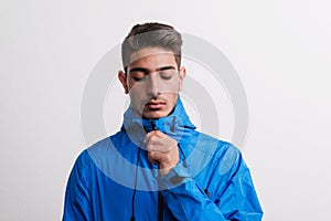 Portrait of a young serious hispanic man with blue anorak in a studio.