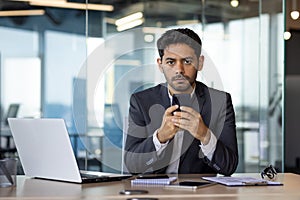 Portrait of a young serious man businessman, executive director sitting in the office at the desk and using the phone