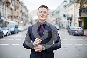 Portrait of a young serious professional. Dressed in a blue slim suit and black shirt, a young handsome businessman stands on a