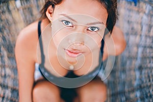 Portrait of young beautiful girl sitting on rattan hammock, blurry background