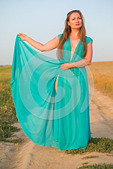 Portrait of a young blonde woman in green dress on a backgr