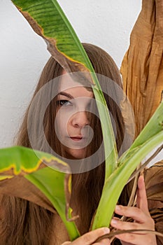 Portrait of a young sexy chubby fat curvy woman with brown hair artfully covered between green and dry, withered decorative banana