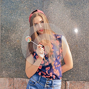 Portrait of young funny fashion girl with red lollipop.