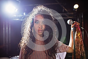 Portrait of young singer holding mic at nightclub