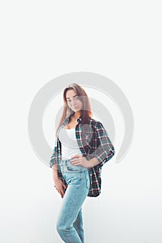 Portrait of a young slender brunette woman in casual clothes posing on a white background. Behind the glow. Vertical. Copy space