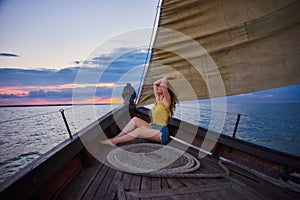 Portrait of young slim girl on sunset in the sea. Young woman meets sunrise on boat