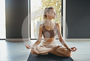 Portrait of young slim sportive woman in sportswear doing yoga exercise on sports mat at yoga meditation center. Concept