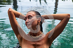 Portrait young slim woman in white swimsuit relaxing in swimming pool