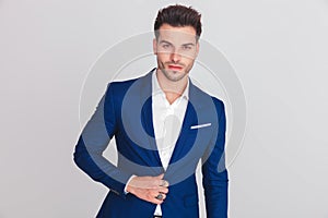 Portrait of young smart casual man buttoning his blue suit