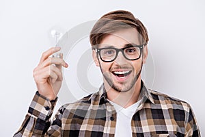 Portrait of young smart man with great idea holding bulb of lamp and excited open mouth