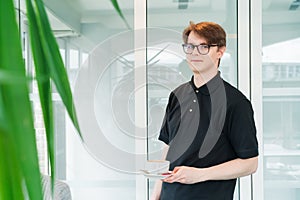 Portrait of young smiling affable waiter carrying on coffee cup to client table in cafe. Hospitality service job