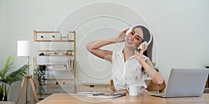 portrait of young smiling asian woman in headphones listening to music at home