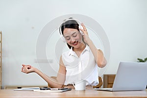 portrait of young smiling asian woman in headphones listening to music at home