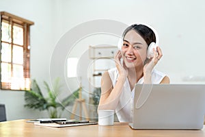 portrait of young smiling asian woman in headphones listening to music at home