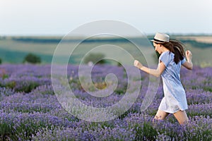 Portrait of young smiling beautiful woman in blue dress, hat on purple lavender flower blossom meadow field outdoors on