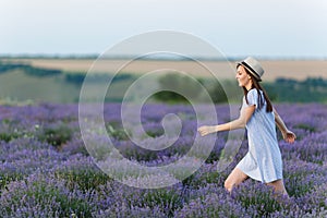 Portrait of young smiling beautiful woman in blue dress, hat on purple lavender flower blossom meadow field outdoors on