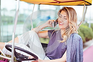 Portrait of a young smiling blonde hair woman sitting on a rickshaw or a golf car
