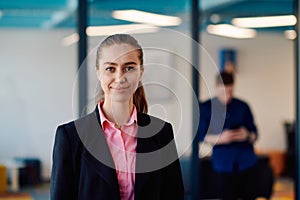 Portrait of young smiling business woman in creative open space coworking startup office. Successful businesswoman