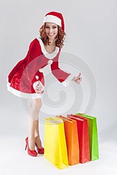 Portrait of Young Smiling Caucasian Ginger Santa Helper Girl with Colorful Shopping Bags