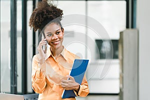 Portrait of a young, smiling, and cheerful African American businesswoman working in a casual office, holding a