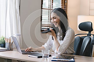 Portrait of a young, smiling, and cheerful entrepreneur working in a casual office, effortlessly multitasking by making