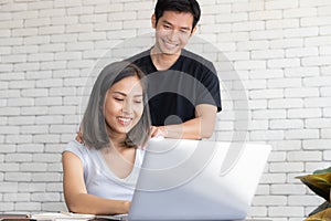 Portrait of young smiling couple working with laptop at home, A man massage shoulder of a girl