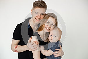 Portrait of young smiling family in dark clothes with plump cherubic baby infant toddler standing on white background. photo