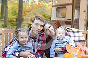 Portrait of a young smiling family while hugging near house on wheels