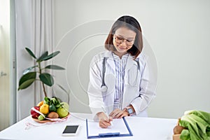 Portrait of young smiling female nutritionist in the consultation room. Dietitian working on diet plan