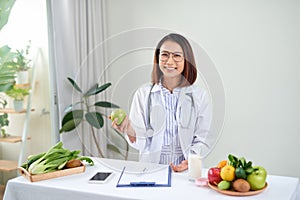 Portrait of young smiling female nutritionist in the consultation room. Dietitian working on diet plan