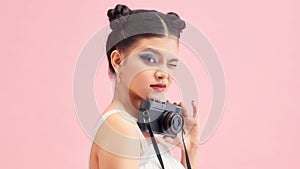 Portrait of young smiling female photographer posing with digital camera