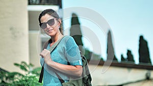 Portrait of young smiling female traveler in sunglasses medium shot