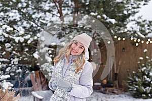 Portrait of a young smiling girl in a pink hat against the background of a large pine tree