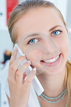 Portrait of a young smiling girl talking on the mobile phone .