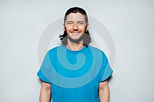 Portrait of young smiling man in blue shirt on background of grey textured wall.