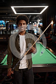 Portrait of young smiling man holding cue
