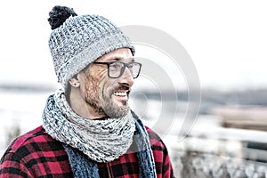 Portrait of young smiling man profile in glasses and warm knitted clothes for city man.