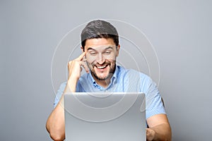 Portrait of young smiling man sitting at the desk with laptop